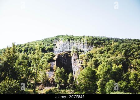 small cave in a pine forest mountain against blue sky Stock Photo