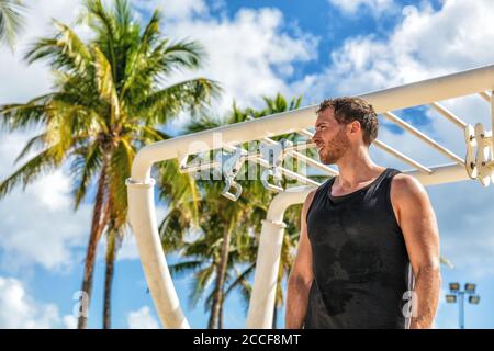 Outdoor calisthenics gym park male athlete working out on monkey bars outside in summer. Man workout Stock Photo
