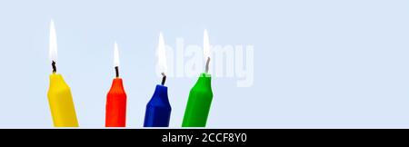 Colorful burning candles against a light blue background Stock Photo