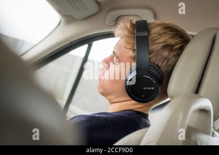Boy (16 years) with headphones in a car Stock Photo