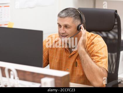 Online working concept. Smiley man with headset having online conversation. Business portrait. Stock Photo