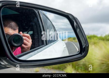 Road trip taking a photo reflected in side view mirror Stock Photo