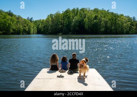 Family and dog on the edge of a dock on a lake Stock Photo