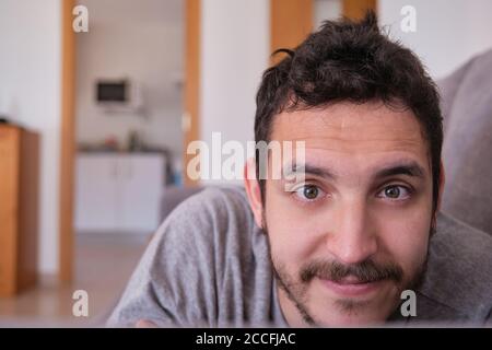 Portrait of a young caucasian handsome man lying on a sofa at home. Domestic life concept. Stock Photo