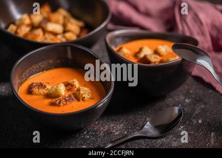 Delicious healthy tomato cream soup on the grounge dark background Stock Photo