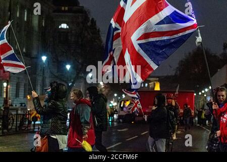 London,England. A small group of leave supporters waving flags seen crossin the street in Whitehall walking to Parliament Square to celebrate the United Kingdom's exit from the European Union at 11 pm on Friday 31st January 2020, based on the referndum from June 23rd, 2016. Stock Photo