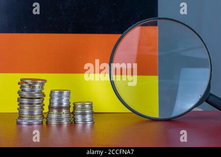 Magnifying glass and coins in front of Japan flag, country economy