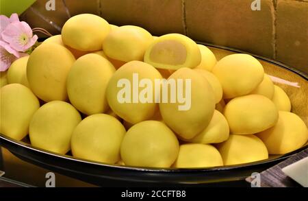 Yellow pieces of round fresh tasty bread with sweet fillings on display at an Asian bakery Stock Photo
