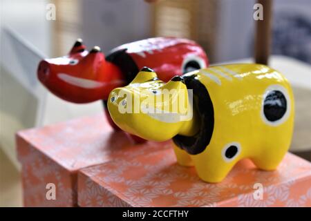 A yellow and a red cow souvenir with a black collar and black spots on top of orange boxes Stock Photo