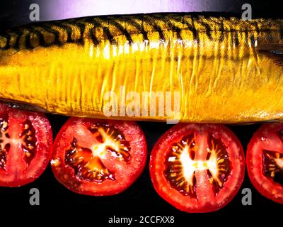 Smoked fish mackerel and tomatoes on a black background. Stock Photo