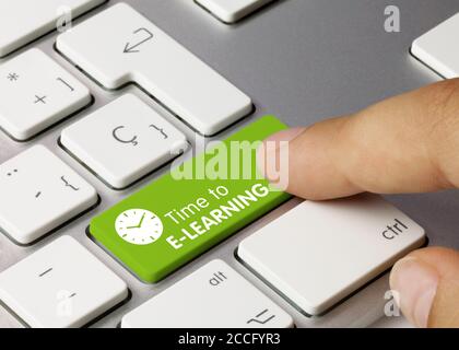 Time to E-LEARNING Written on Green Key of Metallic Keyboard. Finger pressing key. Stock Photo