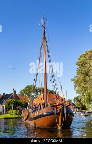 Heeg, Netherlands - August 05, 2020: Tjalk sailing boat leaving for a trip from water recreation village Heeg in Friesland in the Netherlands Stock Photo