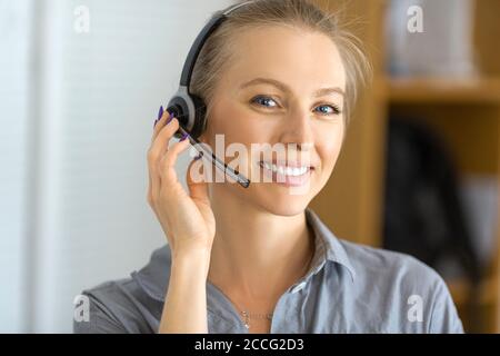 Portrait of a smiley woman with headset working in a call center. Close up. Stock Photo