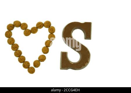 Dutch traditional baked pepernoten in the shape of a heart, with a chocolate letter s next to it on a white background.  Treats that are given Stock Photo