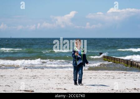 Boy runs along the beach with a cell phone laughing Stock Photo