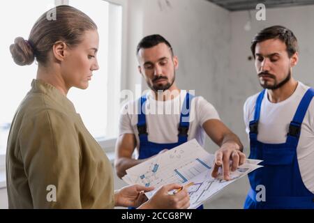A owner of a apartment talking with the builders and considers the scheme of the house Stock Photo