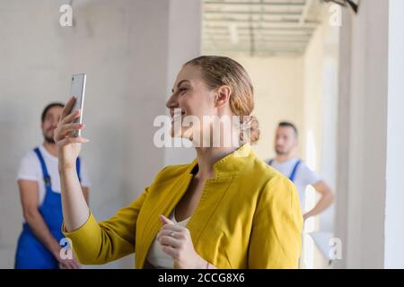 Woman makes a photo on the phone of the work of builders Stock Photo