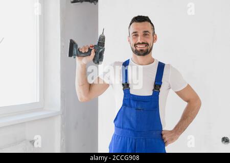 A man holds a drill in his hand and looks at the camera Stock Photo