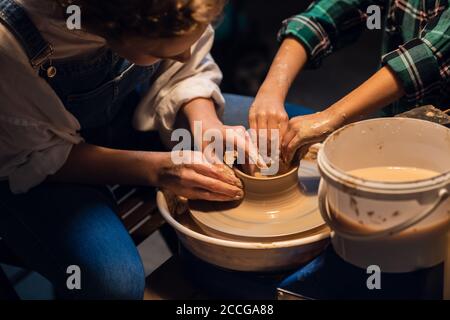 a young mother with a charming son in a pottery workshop sculpting a vase Stock Photo