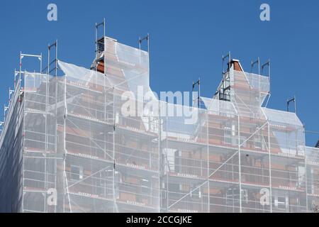 White tarpaulin, construction site, scaffolding, house facade, blue sky Stock Photo