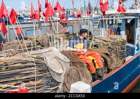 Fishing ship with young fisherman repairing nets Stock Photo