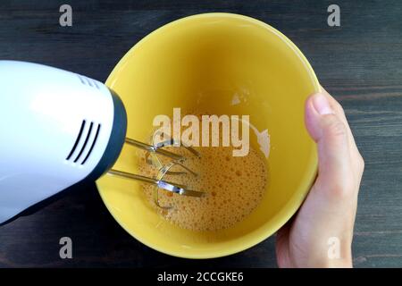 Closeup eggs being beaten by electric egg mixer in a mixing bowl Stock Photo
