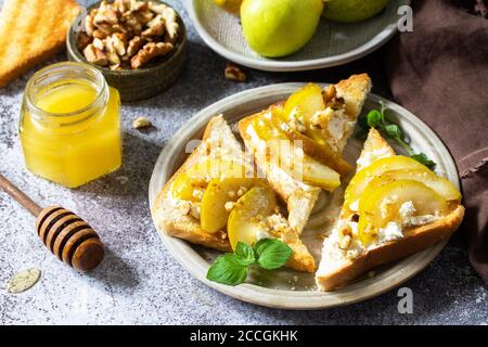 Healthy breakfast or snack, antipasto. Grill toast with caramelized pear and ricotta on a stone or slate countertop. Stock Photo