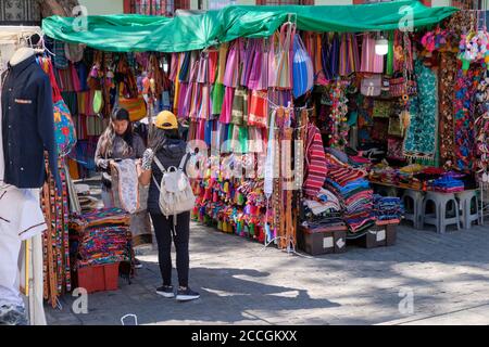 Mexican market stall selling local craft material blankets and clothing in Oaxaca Stock Photo