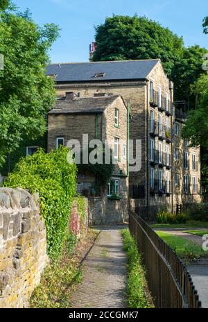 Summer view of an attractive path leading towards a Victorian mill building now converted into flats in Bingley, West Yorkshire Stock Photo