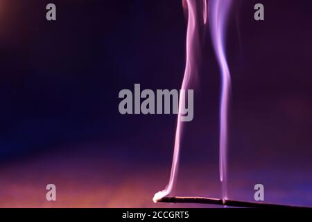 Closeup of a burning incense under the lights against a blurry background Stock Photo
