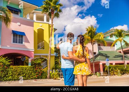 Couple on winter vacation taking pictures of pastel colored beach houses cottages in tropical holiday destination Fort Myers, Florida. Man tourist Stock Photo