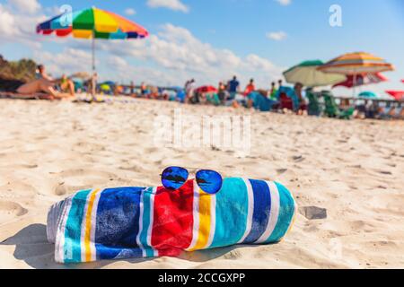 Beach towel and fashion sunglasses on Florida beach background -summer vacation travel concept copy space. Crowded popular USA destination for Stock Photo