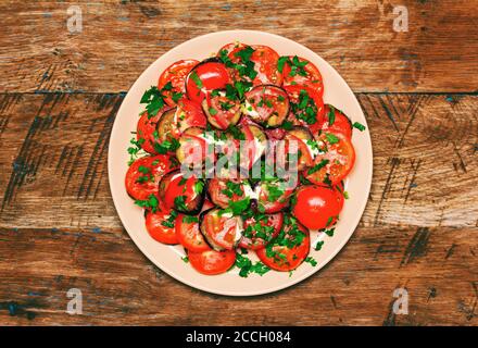 fried eggplant with tomato, garlic and mayonnaise on a wooden background, top view close-up Stock Photo