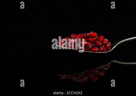 An artistic spoon with red fruit, a black background and reflection Stock Photo
