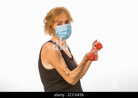 Senior Woman Defiantly Lifting Two Pound Dumbbells During Corona Virus Epidemic Stock Photo