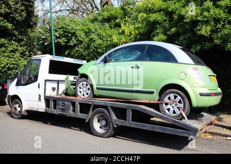 London, United Kingdom, April 21, 2014: A car automobile which has been damaged and wrecked by a crash accident loaded on a vehicle recovery transport Stock Photo