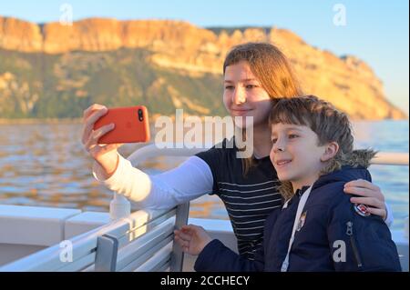 Kids enjoying themselves on a boat tour along the spectacular Calanques National Park at sunset, Cassis FR Stock Photo