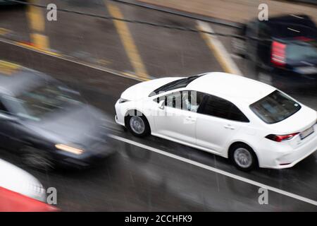 Blurry driving cars on the street hit by the heavy rain with hail, on a rainy day in motion blur panning shot from above Stock Photo