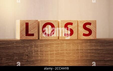 Wooden cubes with LOSS word on wooden table. Financial loss busines concept