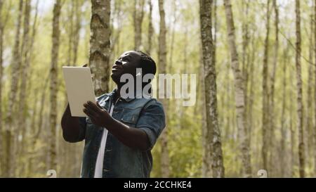 An african man using the tablet in the forest. wireless or future technology concept. High quality photo Stock Photo