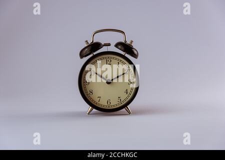 Still life with old clock on desk with books, alarm clock, glasses and white background Stock Photo
