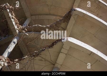 Old grey cracked and broken concrete part of slab with armature rusted bars in old unfinished construction site Stock Photo