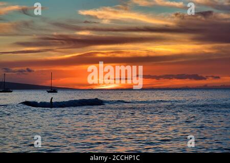 Lone surfer silhouetted at sunset at Lahaina harbor on Maui. Stock Photo