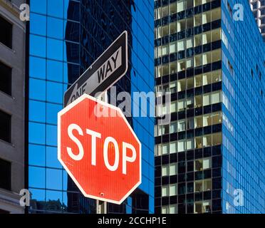 Stop sign on a street of New York City with blurred modern buildings in background, selective focus, USA. Stock Photo