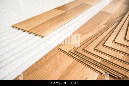 Tiles of light brown laminated floor with wooden effect laying on white base foam, ready to be installed Stock Photo