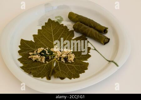 Wraps,rolling of wet grape leaves in white plate,Traditional Turkish Food preparation,above view Stock Photo