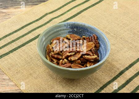 Roasted pecan nut halves and pieces on ceramic bowl on place mat Stock Photo