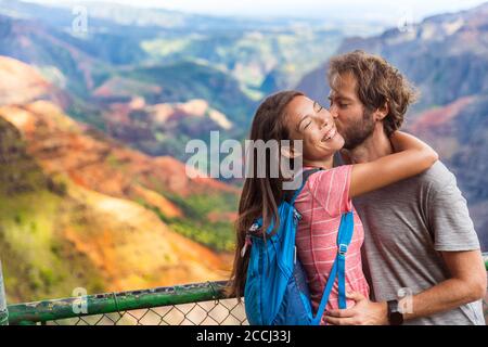 Couple in love kissing on nature travel hiking in Hawaii mountains. Young hikers people happy together. Interracial backpacking lovers kiss portrait Stock Photo