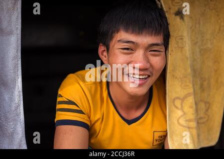 Hoi An / Vietnam - January 18, 2020: portrait of young vietnamese sitting in bus trunk smiling Stock Photo
