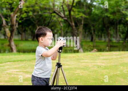 Asian baby boy taking photo graphy in nature by DSLR camera and tripods Stock Photo
